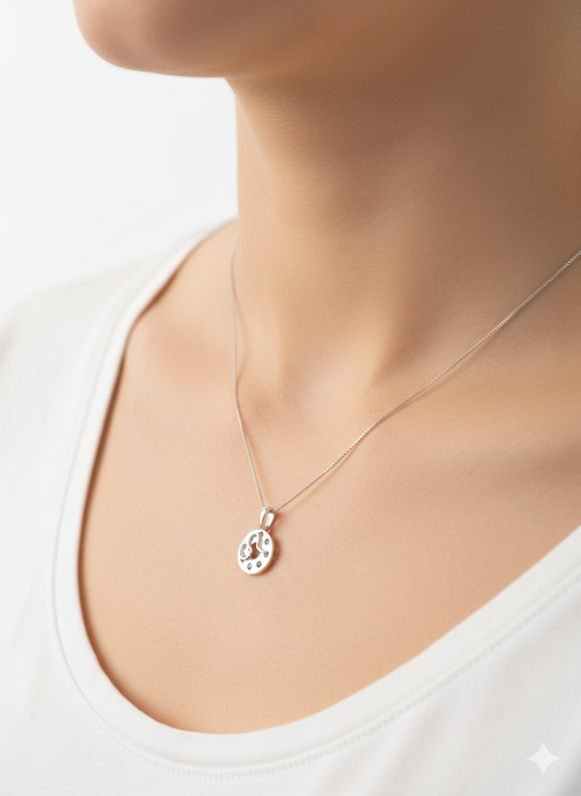 Silver necklace with a bobbin pendant on a person wearing a white top