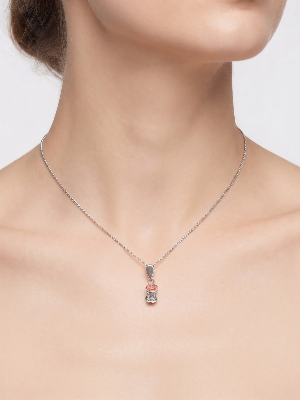 Lady wearing a cotton reel pendant against a white background